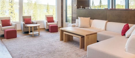 A modern living room with a large sofa, two armchairs, a coffee table, and a rug.