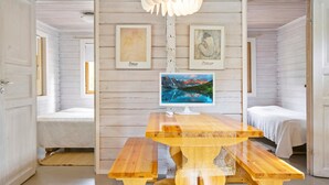 Une pièce aux murs en bois, avec une table en bois sur laquelle se trouve un téléviseur, et deux lits.