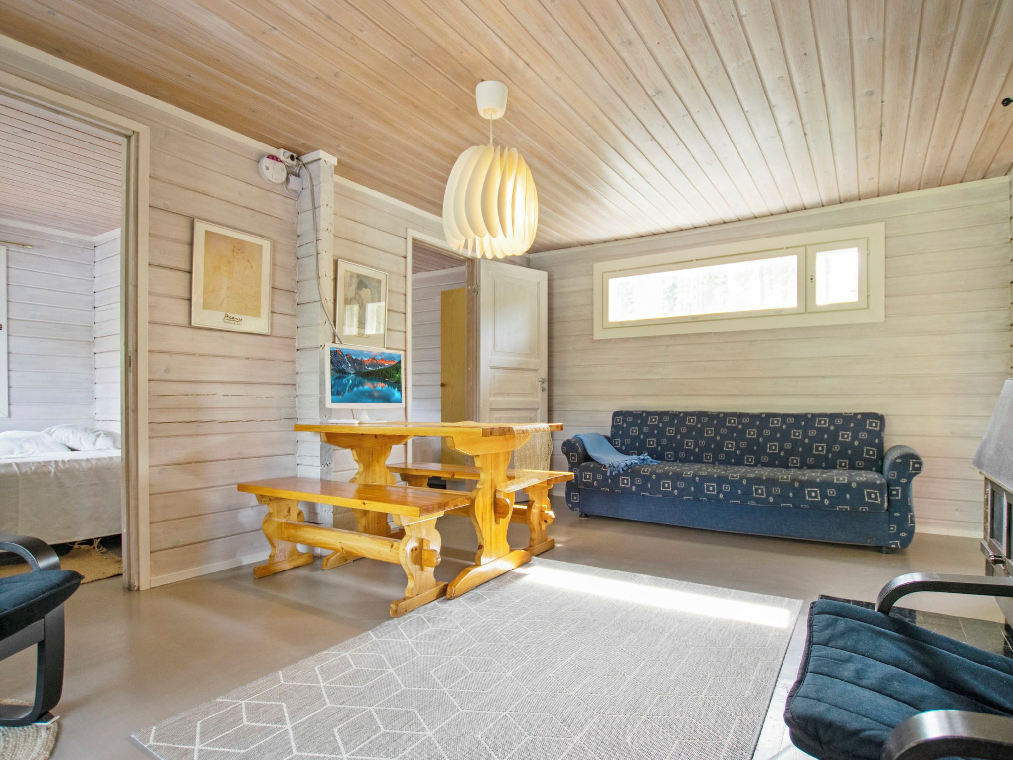 Ein Zimmer mit Holzbalkendecke, einem Esstisch, einer Couch und einem Bett.