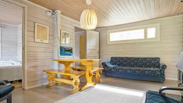 Ein Zimmer mit Holzbalkendecke, einem Esstisch, einer Couch und einem Bett.