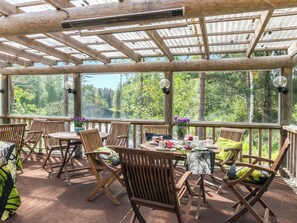 A covered outdoor seating area with wooden furniture and a table set for dining. - Koskisaari, vaikon loma 2 by Interhome (Kaavi)