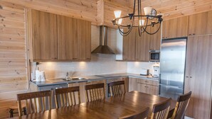 Eine moderne Küche mit Holzausstattung, einem Edelstahlkühlschrank und einem Essbereich mit Holztisch und Stühlen.