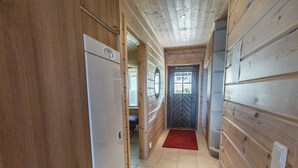 Ein Korridor mit Holzwänden, Fliesenboden und einem Kühlschrank links.