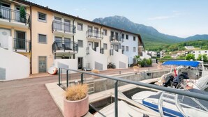 A residential building with balconies, a small garden, and a view of mountains.