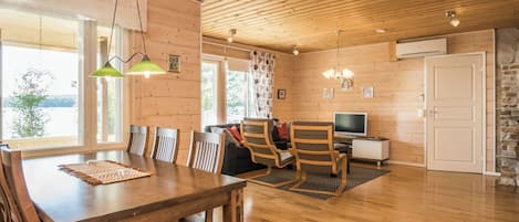 Ein Holzinnenraum mit Essbereich, Sitzgelegenheiten und einem Fernseher.