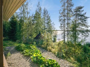 A cabin with a gravel path leading to a dock over water, surrounded by dense forest.
