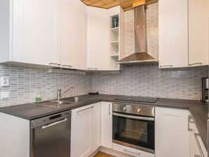 Una cocina moderna con armarios blancos, una campana extractora de acero inoxidable y un horno empotrado.