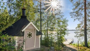 A small cabin with a hexagonal window, surrounded by trees and a lake. - Kärkiniemi by Interhome (Tuusniemi)