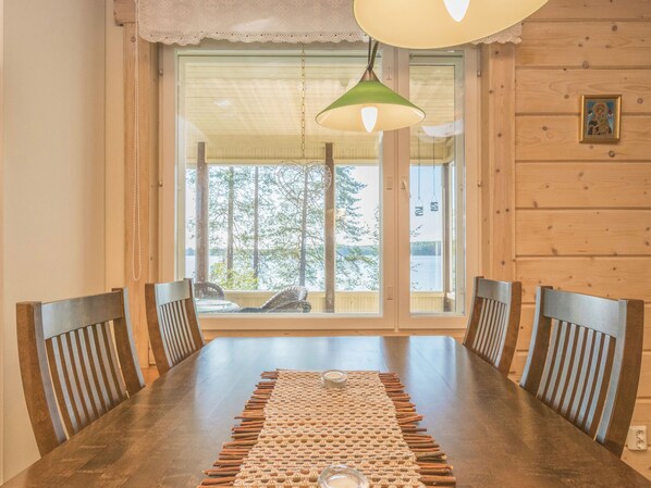 A dining area with a wooden table, four chairs, a woven placemat, and a hanging light fixture.