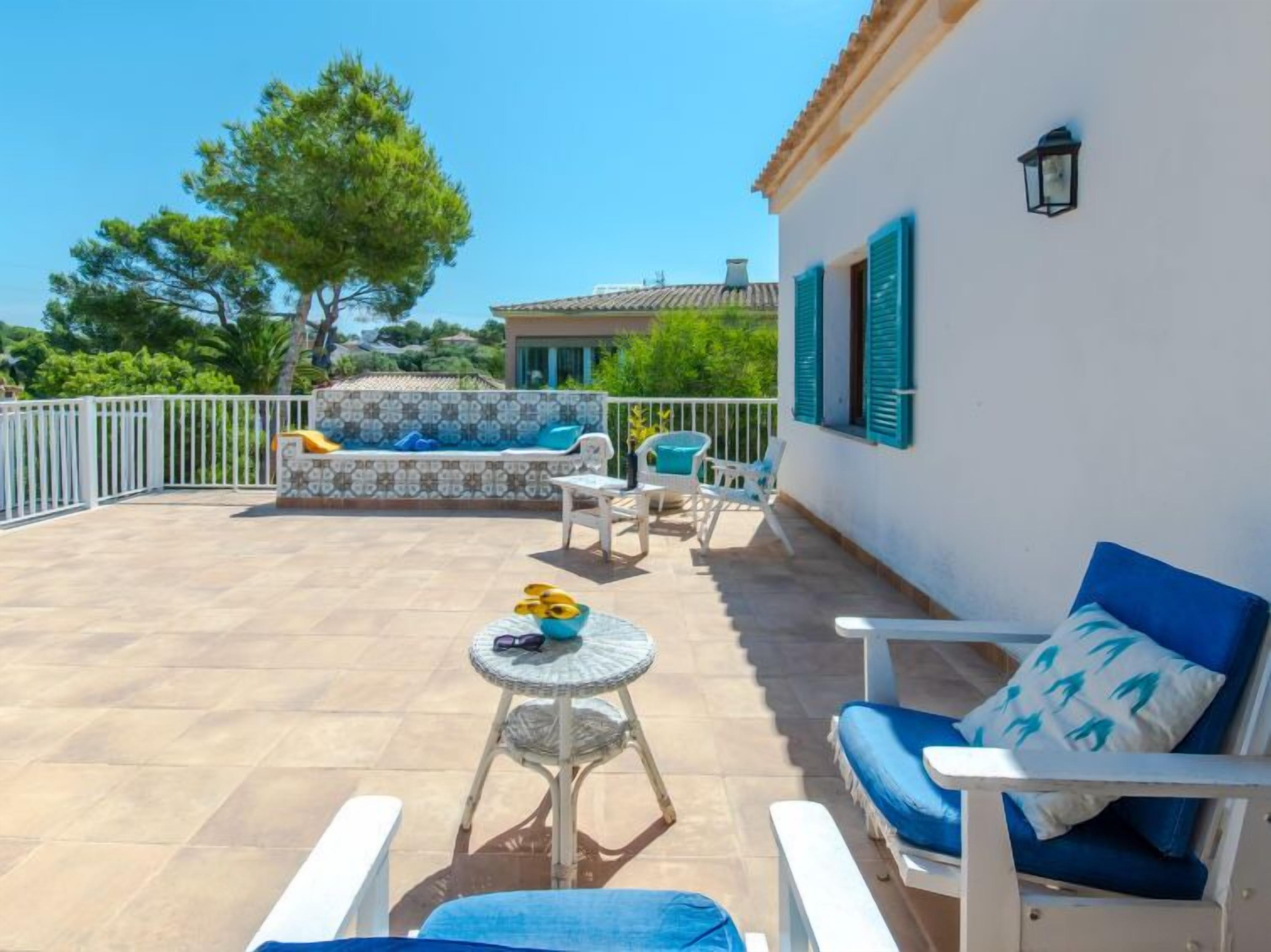 Eine sonnendurchflutete Terrassenanlage mit Schwimmbad, Liegestühlen und einem Tisch.