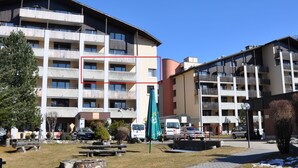 A multi-story hotel with balconies, a parking area, and a small garden. - Disentiserhof Hönig by Interhome (Disentis)