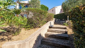 Una serie di gradini in pietra che conducono a un edificio, immersi nel verde con un cielo sereno.