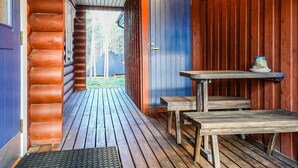 Une cabane en bois avec un porche, une porte bleue et une vue sur une forêt.