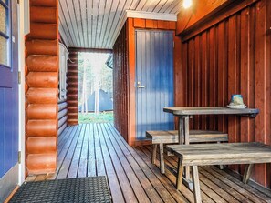 A wooden cabin with a porch, a door, and a small table.
