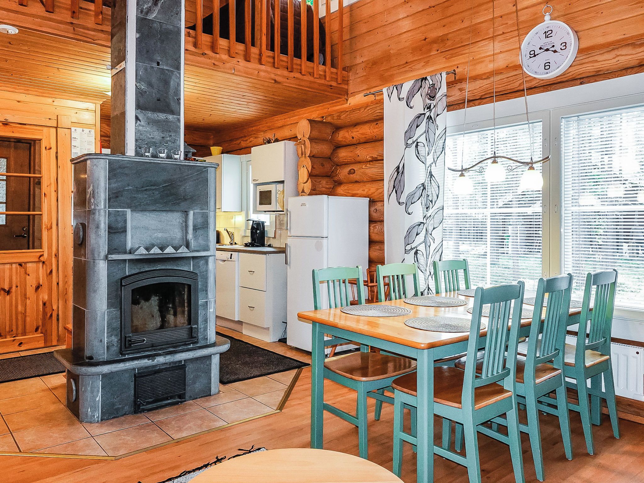 A cozy cabin interior with a stone fireplace, wooden dining table, and chairs.