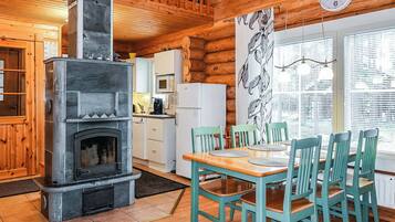 A cozy cabin interior with a stone fireplace, wooden dining table, and chairs.