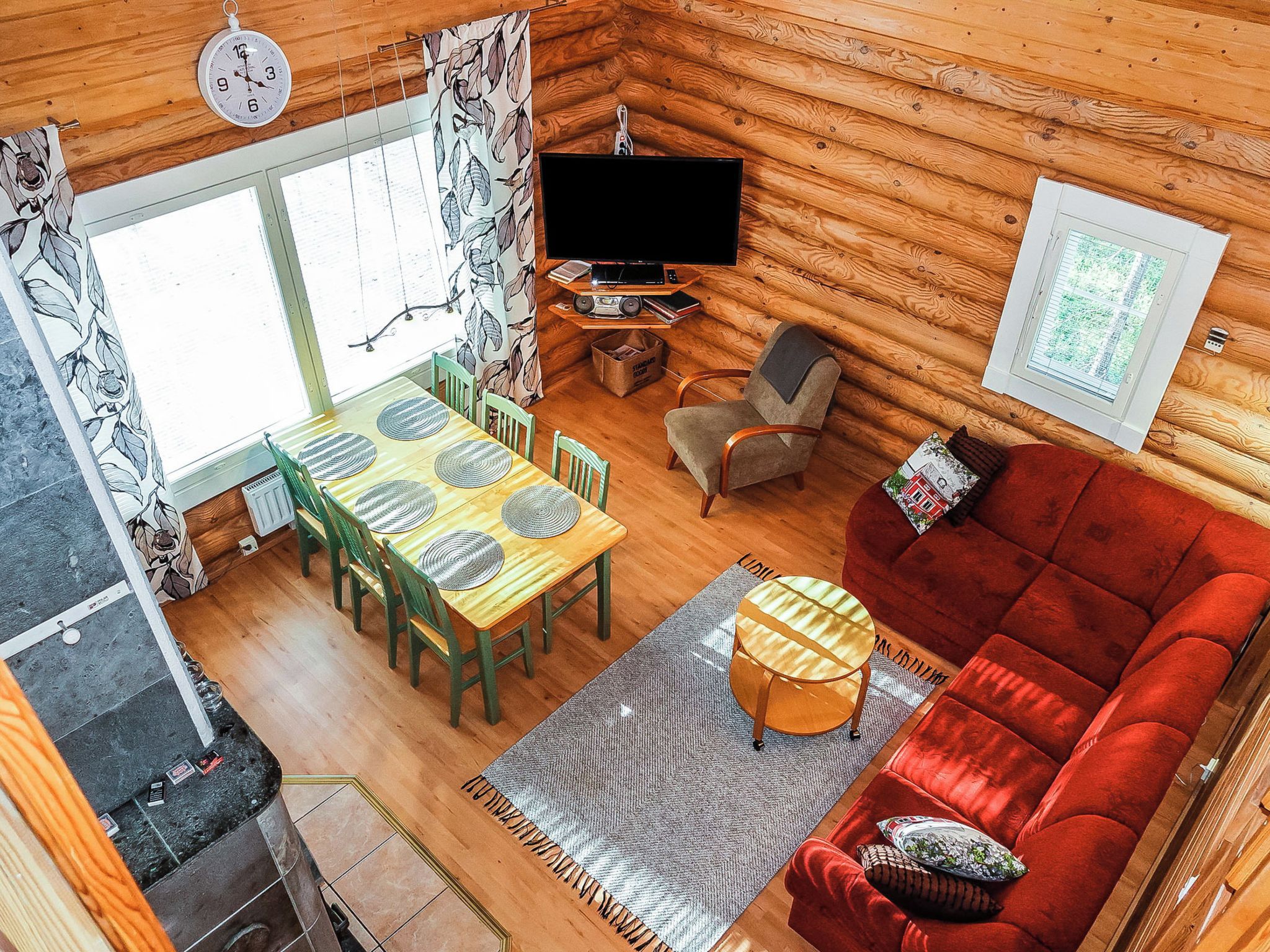 Interior acollidor d'una cabana amb zona de menjador, sofà, televisió i finestra.