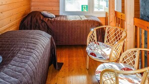 Un chalet confortable avec deux lits, un plancher en bois et une fenêtre équipée de stores.