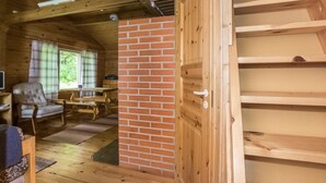 L’intérieur d’un chalet en bois, avec un mur en briques, une porte en bois et un coin repas comprenant une table et des chaises.