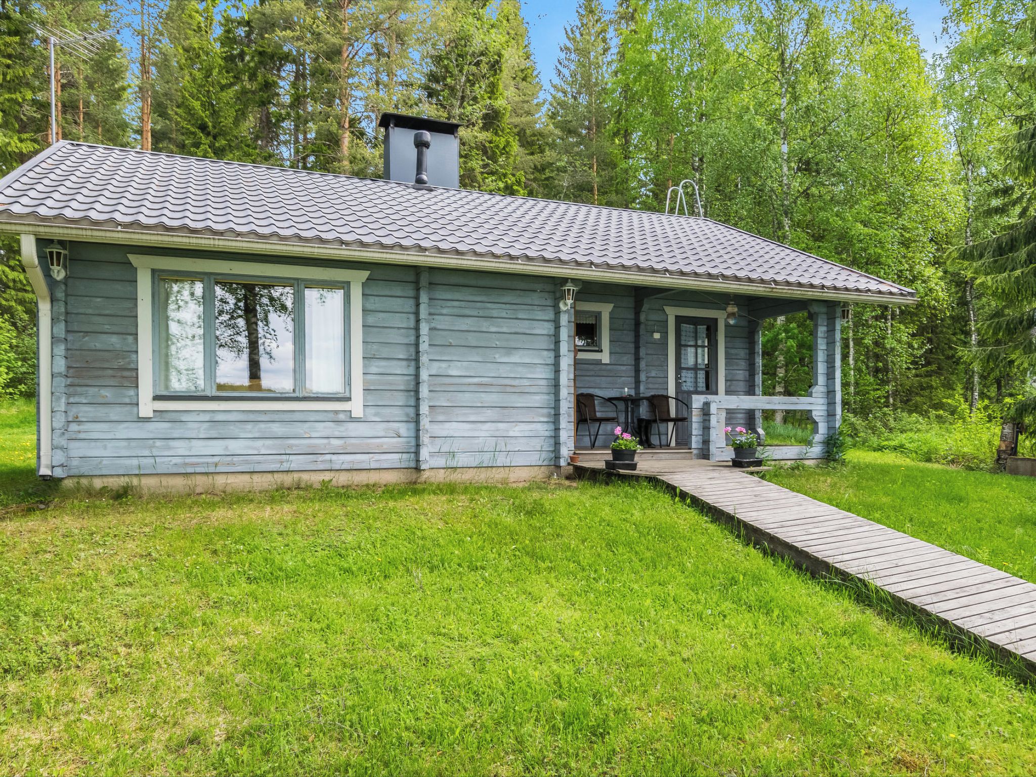 A small, single-story cabin with a porch and a wooden deck.