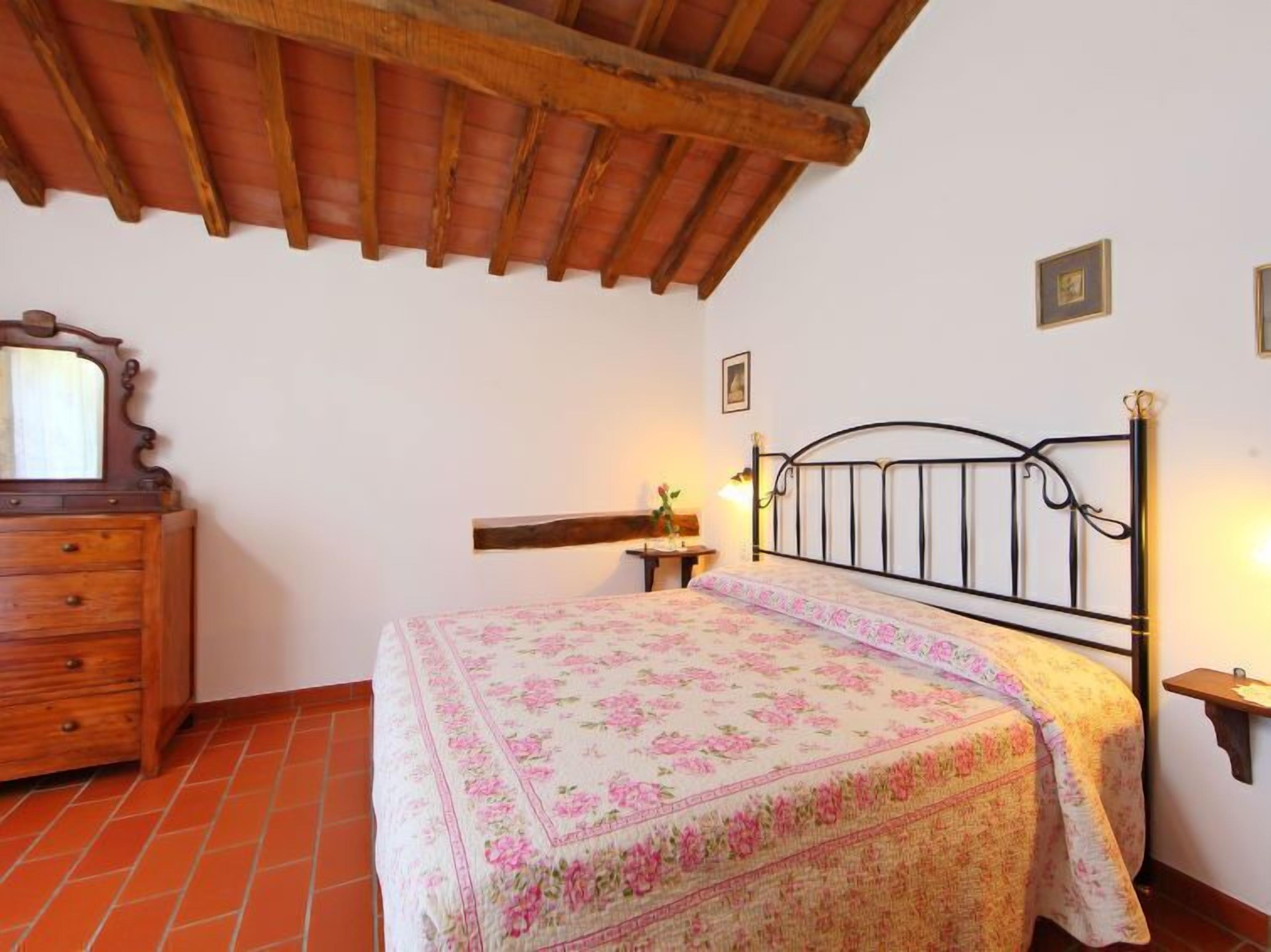 A bedroom with a bed, wooden dresser, and a sloped ceiling.