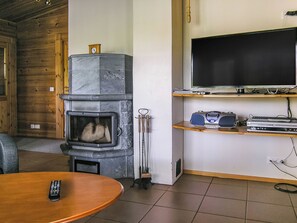 Una sala de estar con chimenea de piedra, un televisor en un estante y un control remoto sobre una mesa.