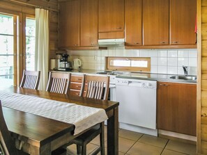 A kitchen with wooden cabinets, a white dishwasher, and a dining table with chairs.