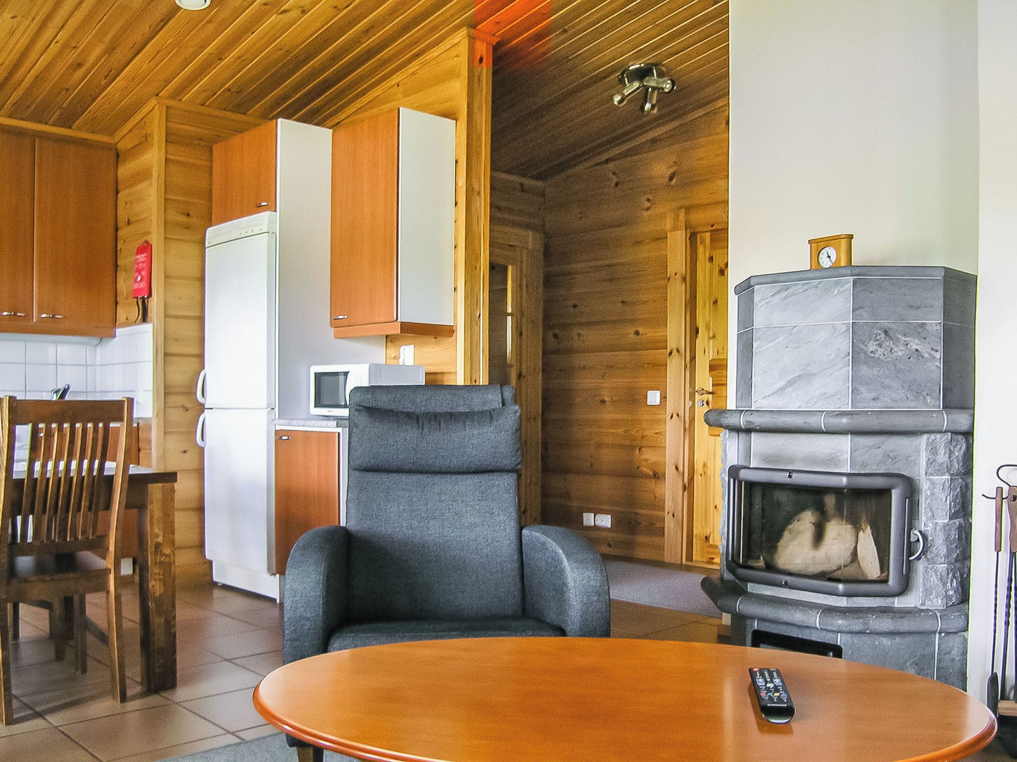 Un intérieur en bois avec une cheminée, une table à manger et un coin cuisine.