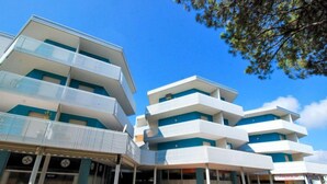 Un edificio moderno de varios pisos con balcones y un área de entrada techada.