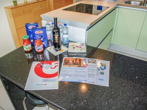 A kitchen counter with various items including a bottle of wine, condiments, and a brochure. - Residenza Moro by Interhome (Ascona)