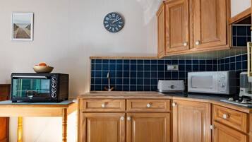 Een koelkast, een magnetron, een oven, kookgerei, borden en bestek