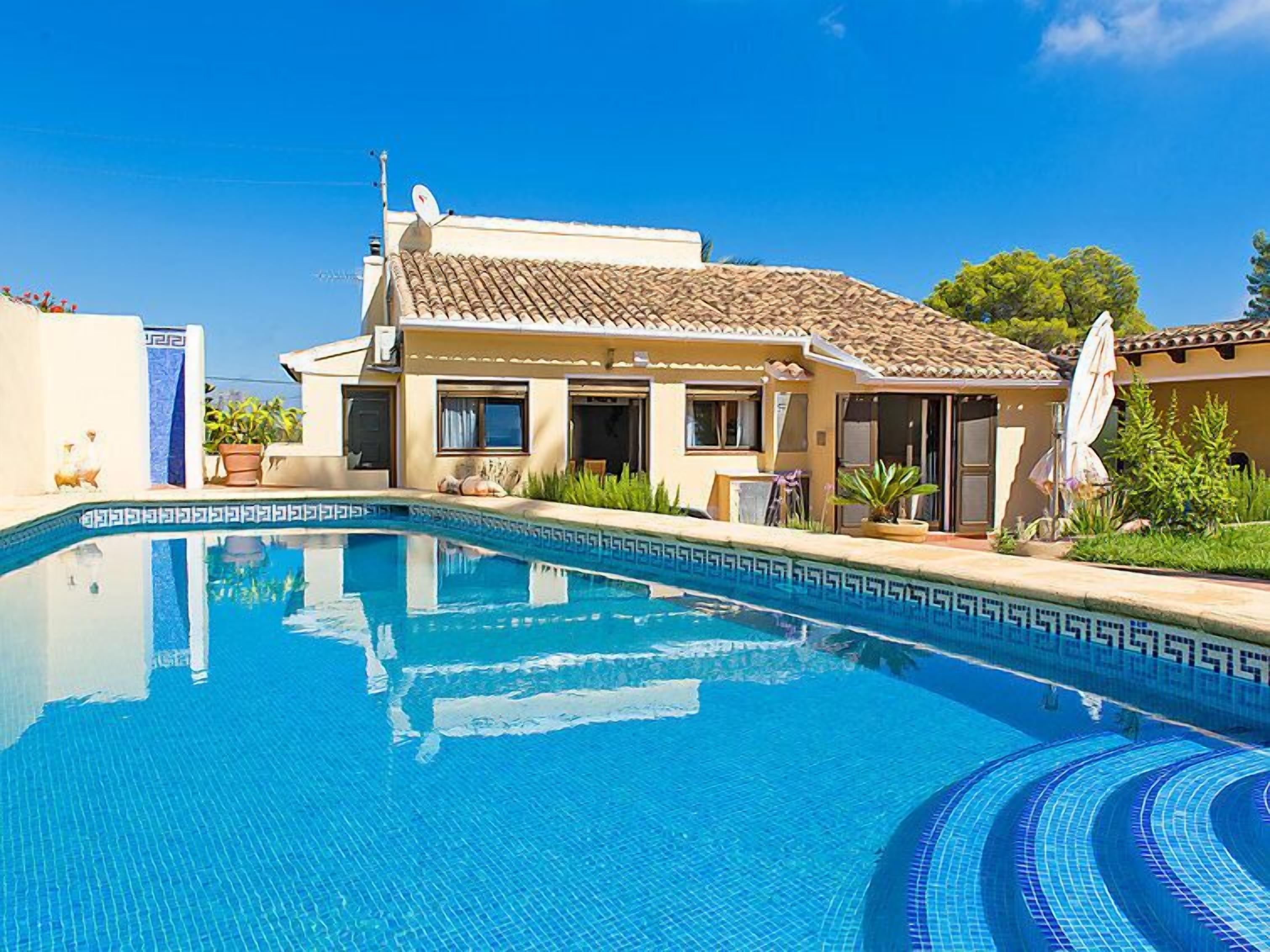 Ein Haus im mediterranen Stil mit Swimmingpool, Satellitenschüssel und Garten.