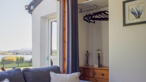 En balkong med en grå soffa, en byrå i trä och en inramad tavla på väggen.