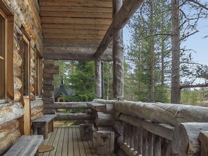 A wooden cabin with a porch, built-in benches, and a view of a forest. - Honkapirtti, vuotunki by Interhome (Kuusamo)