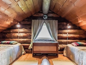 A cozy log cabin room with a central bed, two bedside tables, and a window with curtains. - Honkapirtti, vuotunki by Interhome (Kuusamo)