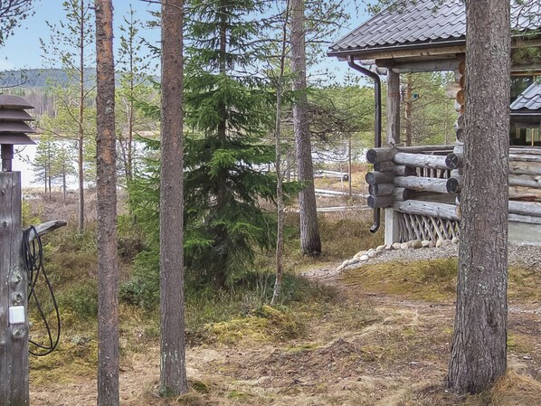 A wooden cabin with a thatched roof, surrounded by tall trees and a clear sky. - Honkapirtti, vuotunki by Interhome (Kuusamo)