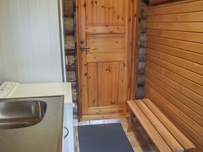 A wooden door with a metal handle, a bench, and a small sink area. - Honkapirtti, vuotunki by Interhome (Kuusamo)