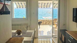Een kamer met uitzicht op zee, een hond en een televisie.