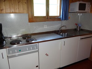 A kitchen with a stove, sink, and microwave.