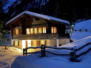 Una cabaña de madera de dos pisos con un balcón, rodeada de nieve.