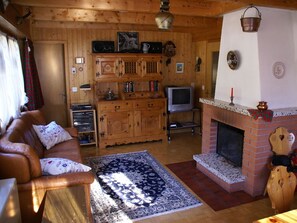 Una sala de estar acogedora con chimenea, muebles de madera y televisor.