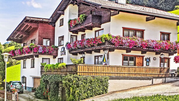 A traditional Alpine-style building with balconies adorned with flowers, a wooden front porch, and a sign indicating a restaurant. - Jägerhof by Interhome (Schwaz)