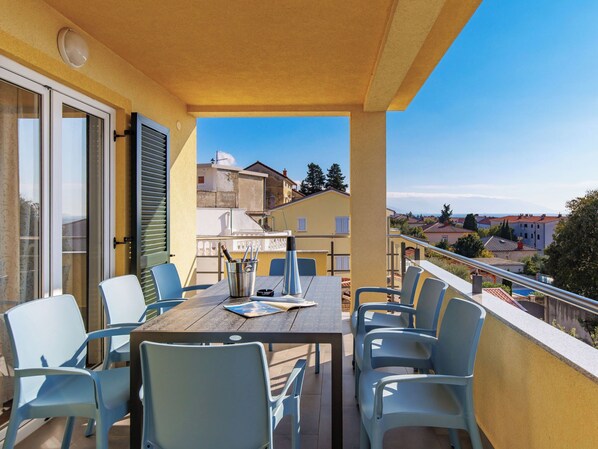 A balcony with a wooden table and chairs, a bottle of wine, and a menu. - Apartment Leko by Interhome (Novi Vinodolski)