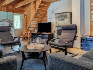 Un salon chaleureux avec un escalier en bois, un téléviseur à écran plat et des sièges confortables.