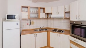A compact kitchen with white cabinets, a microwave, a stove, and a refrigerator. - Plavac Mali by Interhome (Trstenik/Dingač)