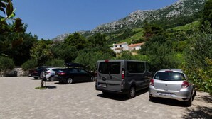 A parking area with several cars, a van, and a building in the background. - Plavac Mali by Interhome (Trstenik/Dingač)