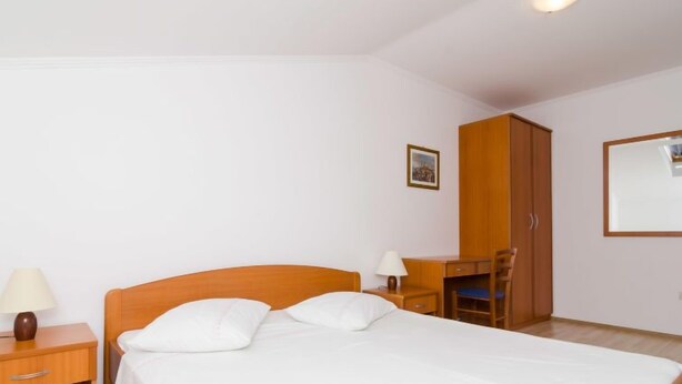 Une chambre à coucher avec un lit, un bureau, une chaise et une armoire.