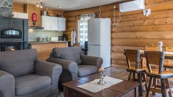 A cozy cabin interior with a fireplace, sofa, dining table, and kitchen area.