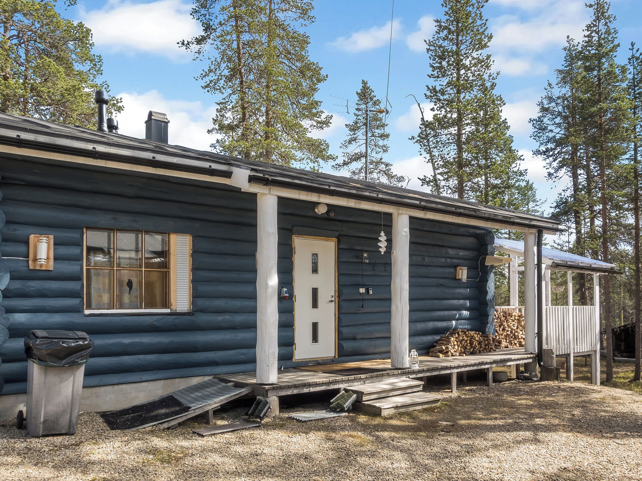 A log cabin with a front porch, a door, and a window.