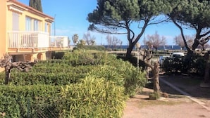 Un bâtiment doté d’un balcon, entouré de haies et d’arbres bien entretenus.
